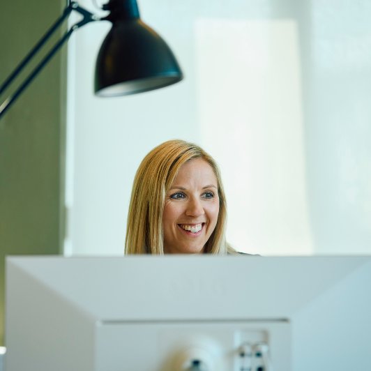 Woman smiling infront of a computer screen