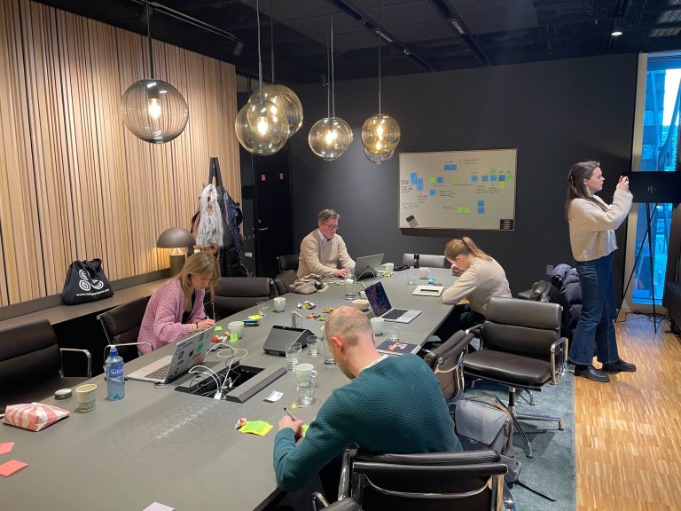 Folk som sitter i et møterom og diskuterer nettsiden til Friluftslivetsår